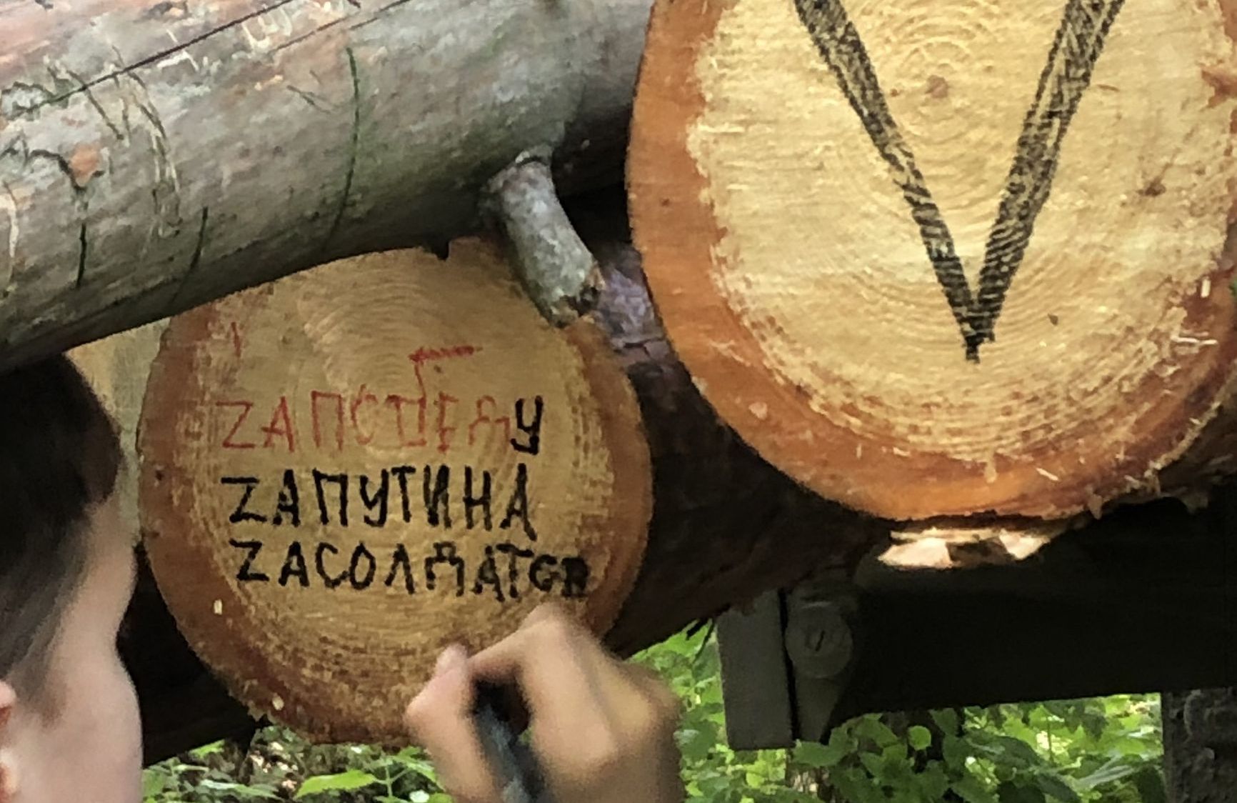 A child paints a log with patriotic slogans